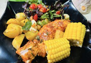 baked tandoori salmon meal with potatoes, salad and corn