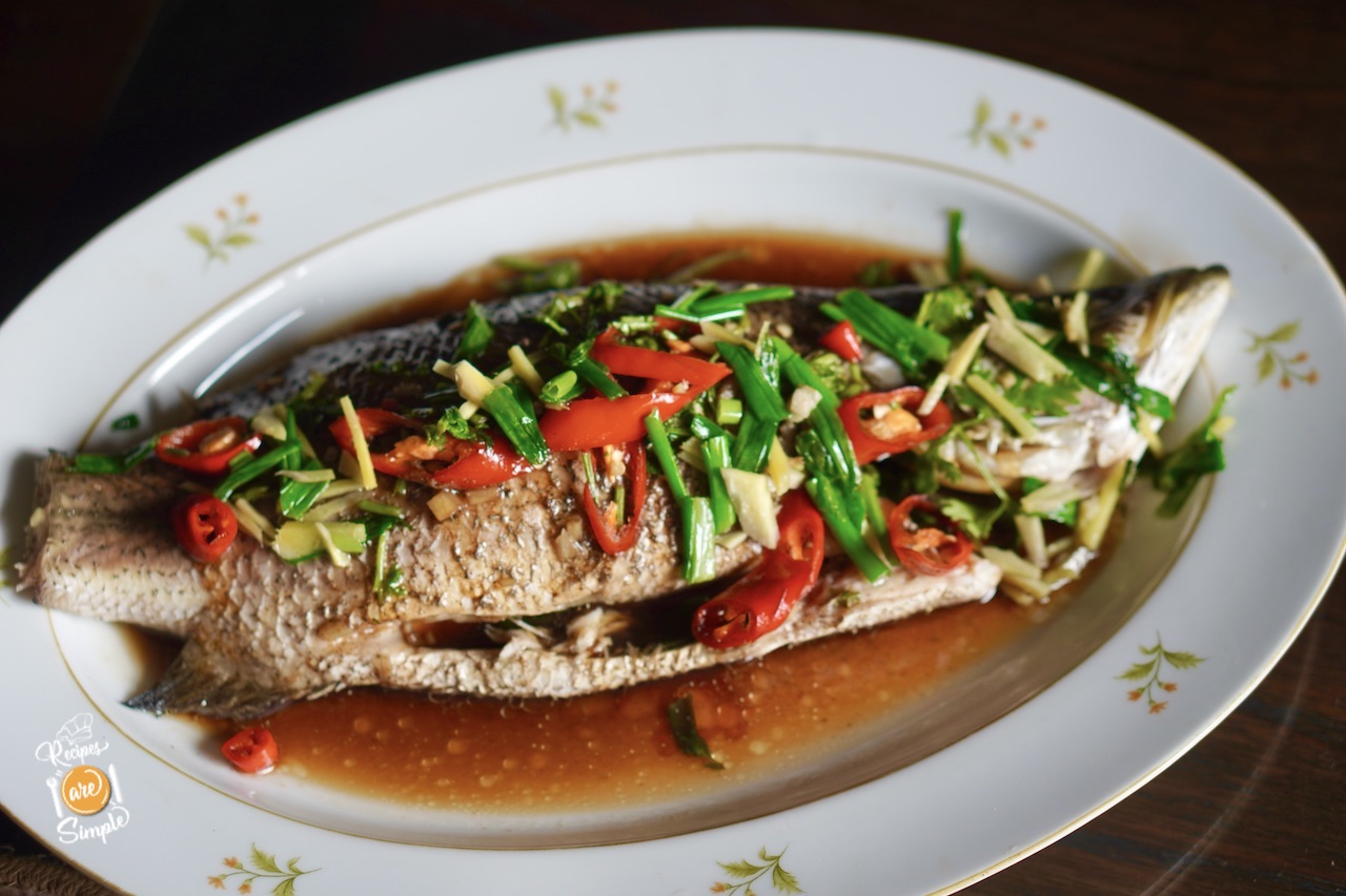 chinese steamed fish plated with ginger, chillies and spring onion and sauce